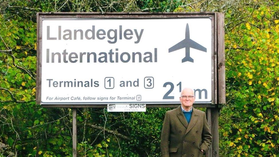 Nicholas Whitehead standing in front of the Llandegley International sign