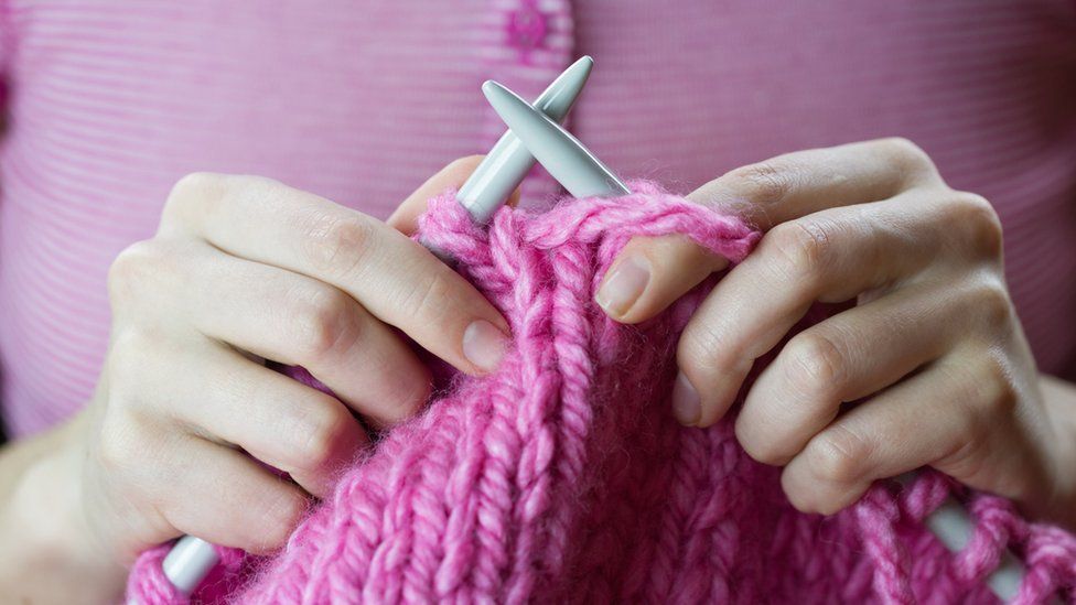 Close up of a female hands knitting pink woolen threads