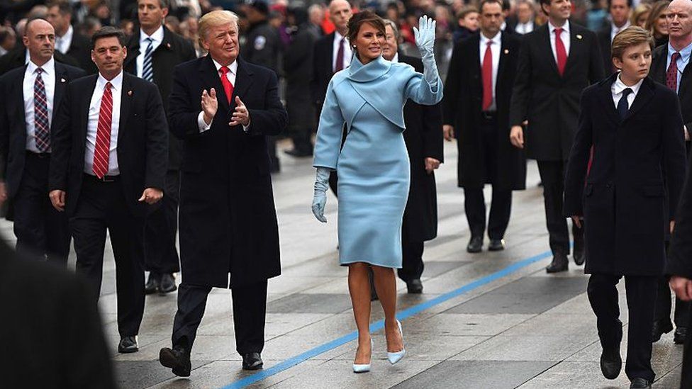 President Donald Trump and First Lady Melania Trump wave during the inauguration parade in Washington.