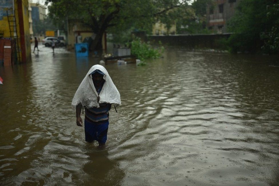 Индийский мужчина пробирается по заболоченной улице после проливных дождей в Ченнаи, Индия, 7 ноября 2021 года.