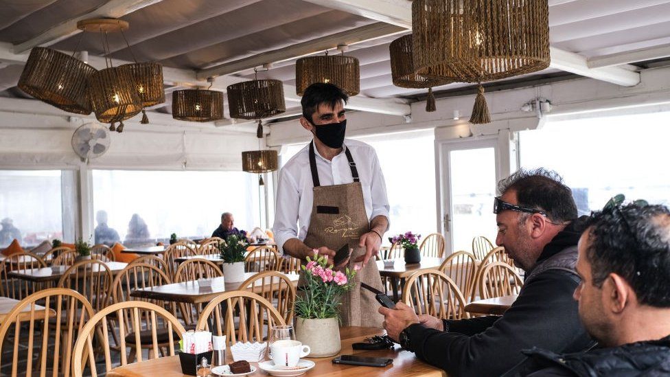 A waiter serves patrons in Mykonos