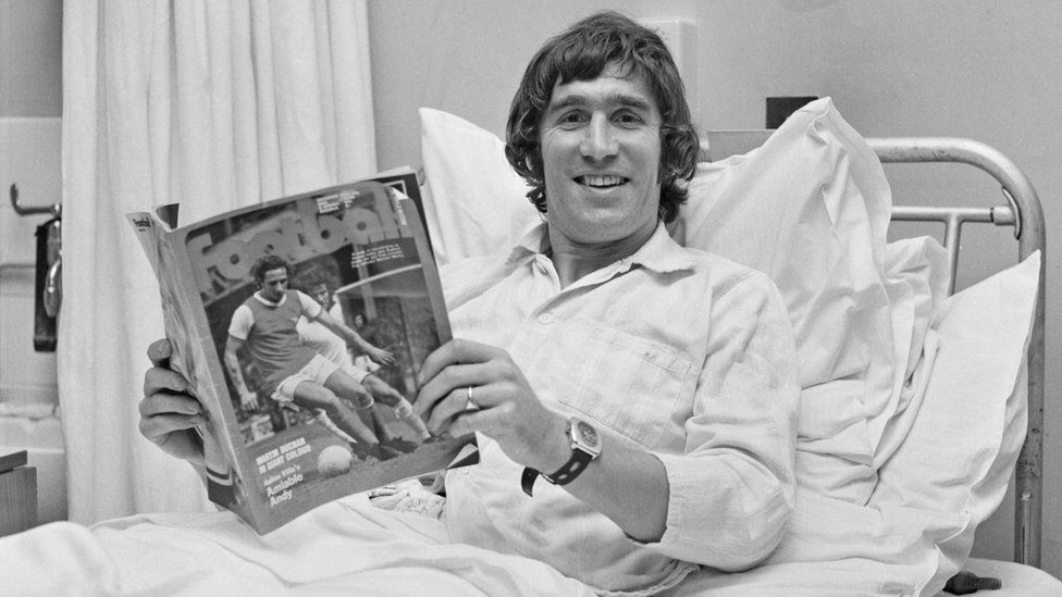 Duncan Forbes in a hospital bed with a football magazine