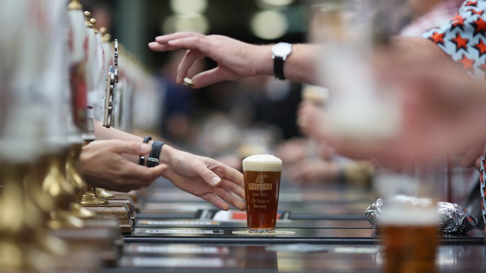 side view of pub bar with hands picking up beer and handing over change