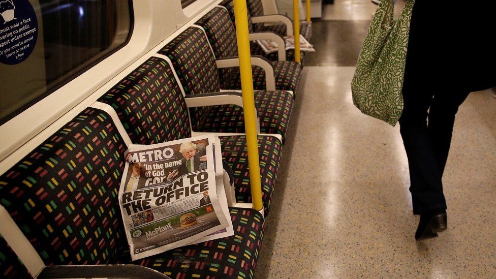 A newspaper, with the headline "Return to the office", on a mostly empty Tube train