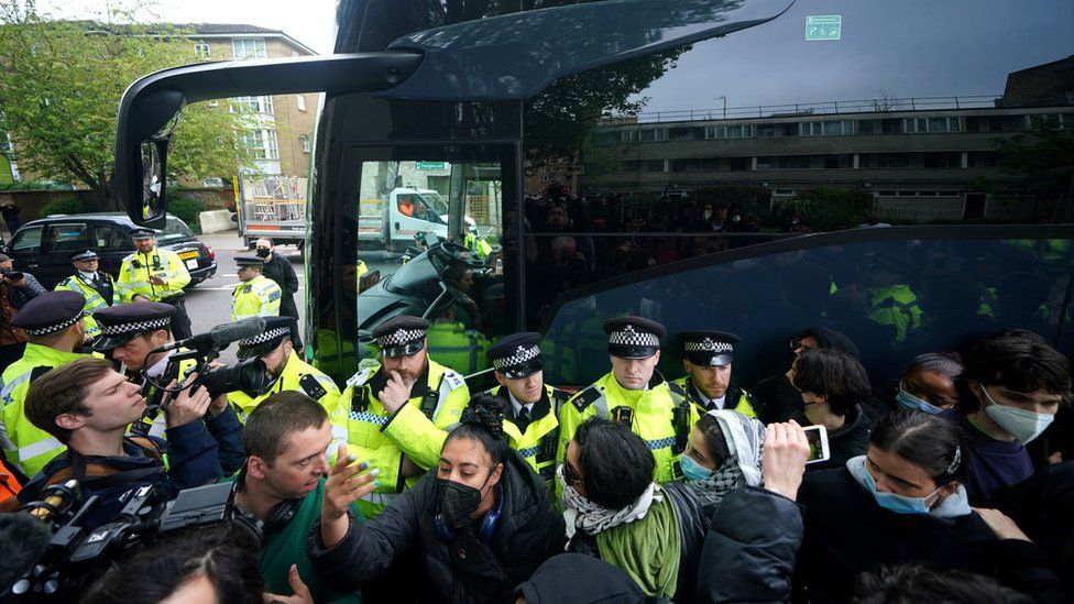 Police try and stop protesters forming a blockade around a coach