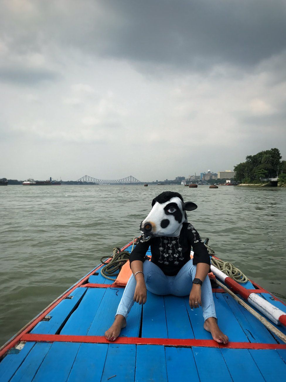 A woman with a cow mask on a boat