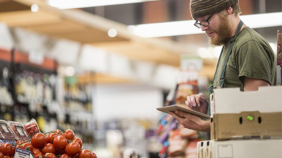 Mann, der Tomaten im Laden zählt