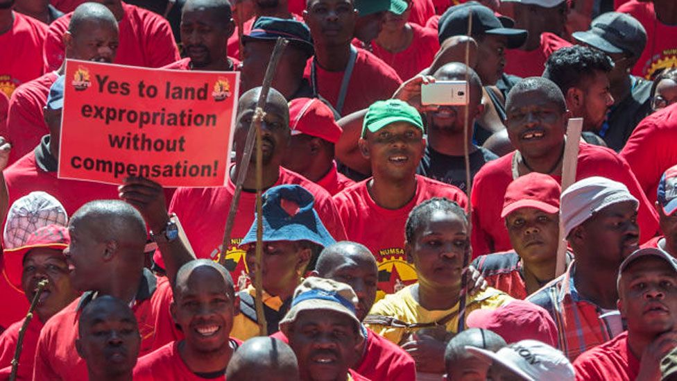A demonstrator in South Africa holds a placard reading "Yes to land expropriation without compensation" as thousands of workers take part in a national strike called by the country's second largest labour union - April 2018