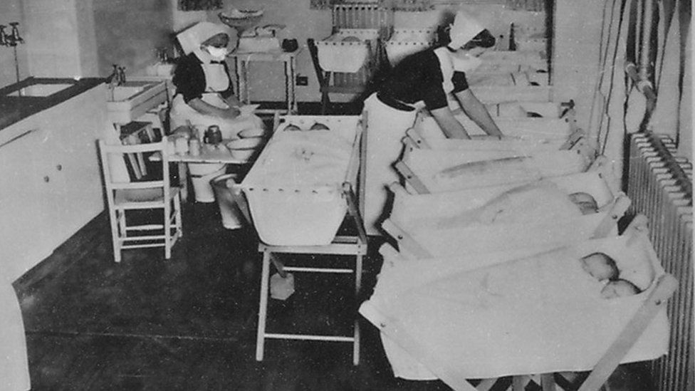 A black and white image showing babies in cots and medical staff at St Peter's