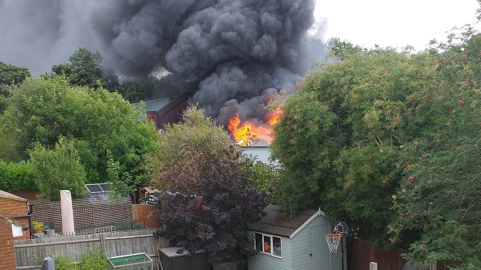 Flames and smoke coming from rooftops during car workshop fire in St Albans, as seen from nearby home