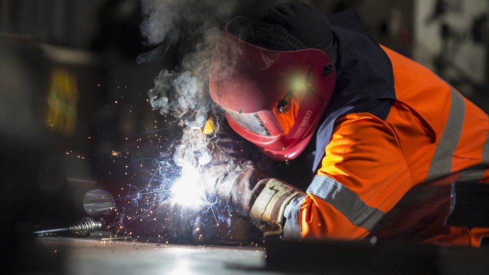 Steel worker cutting metal