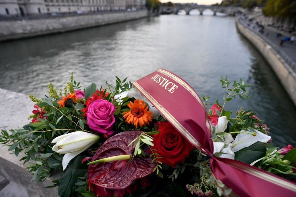 A wreath of flowers is pictured on a bridge above the Seine river.