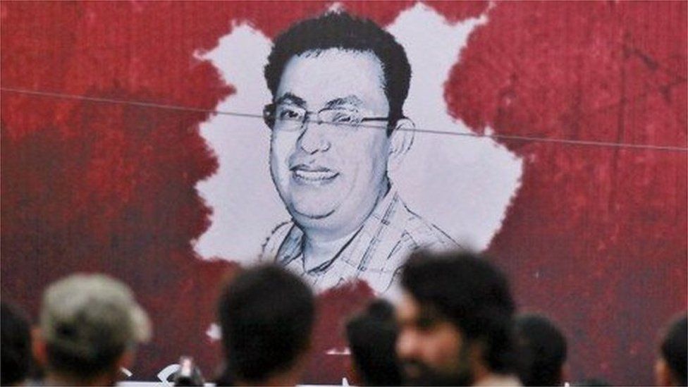 A Bangladeshi activist sets up a light on a poster displaying a portrait of Avijit Roy as others gather during a protest against the Roy in Dhaka, Bangladesh, Friday, Feb. 27, 2015.