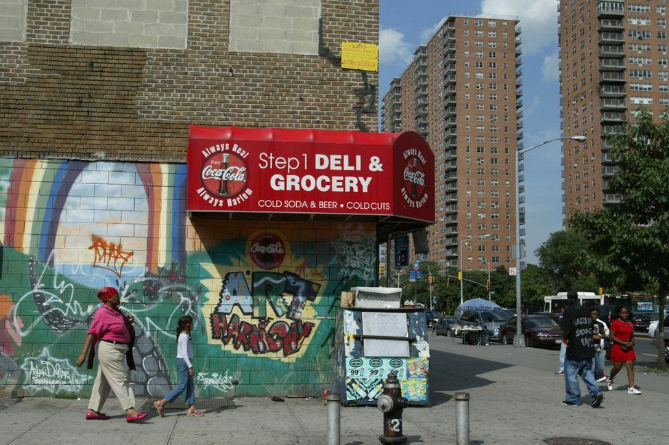 Pedestrians walk past graffiti near public housing in the Harlem neighborhood of New York