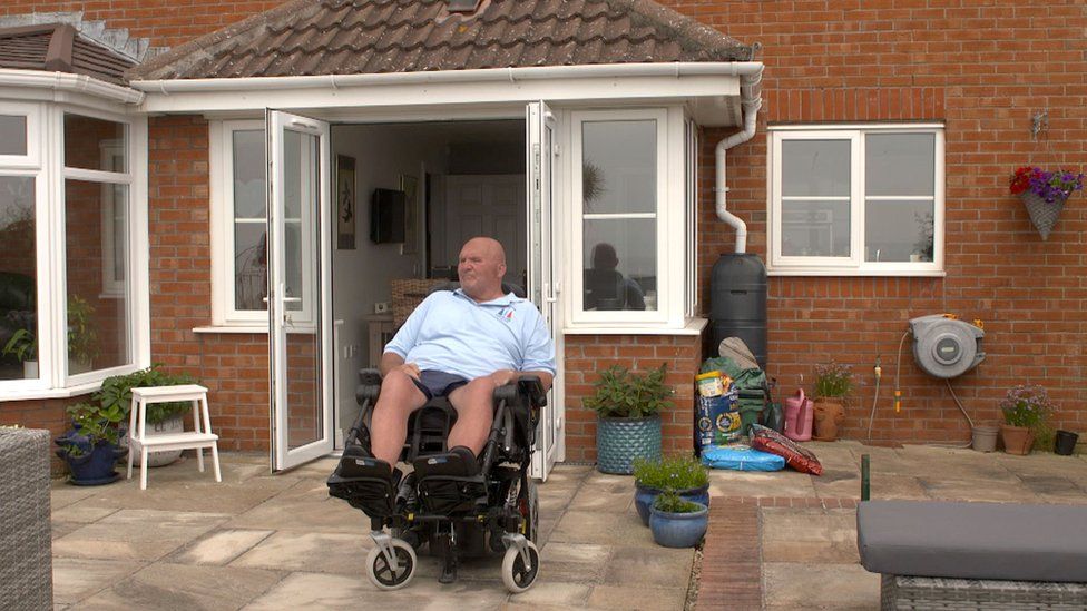 Nigel outside his house in his wheelchair