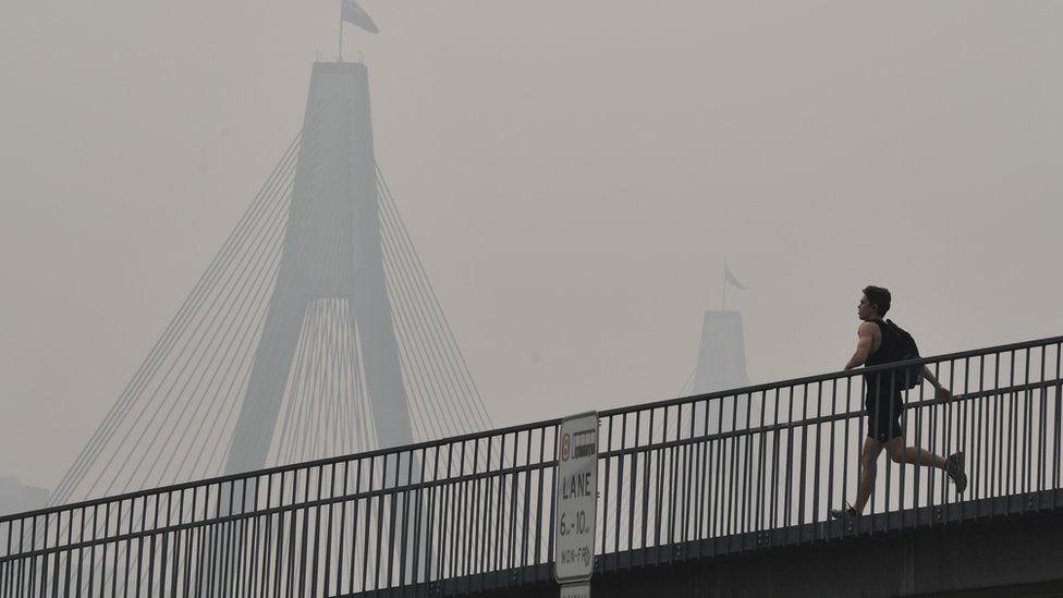 A man runs over a bridge during a smoky haze in Sydney on Tuesday