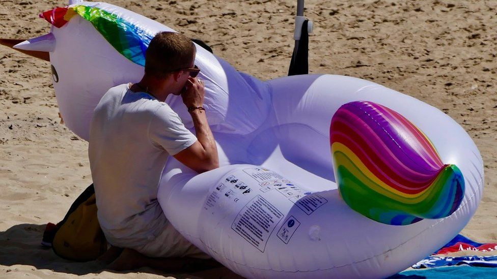 A man blows up an inflatable on a beach in Bournemouth