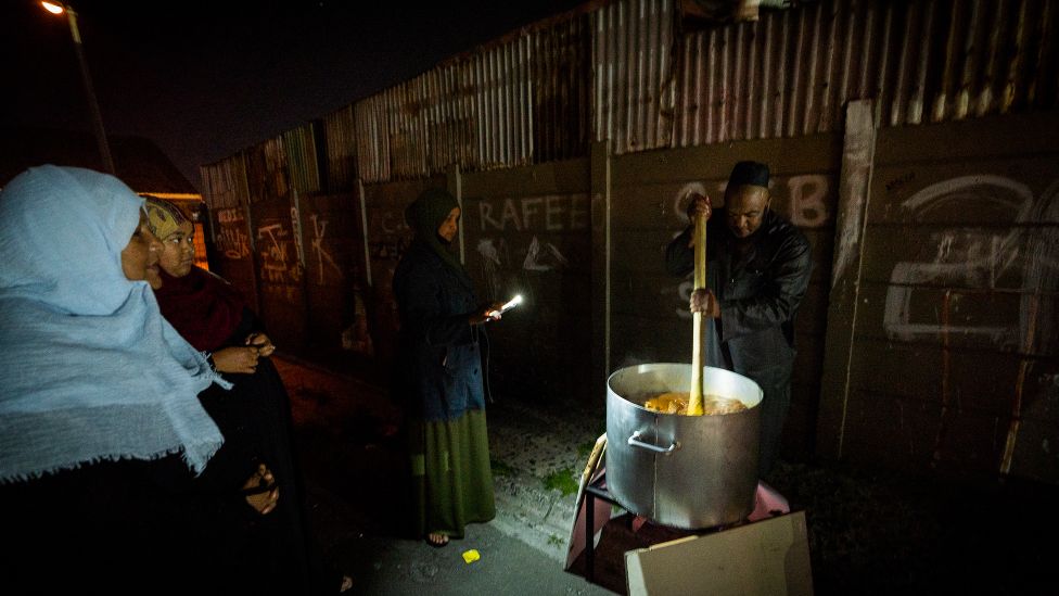 Шейх Самиг помешивает большую кастрюлю с едой в Маненберге, Кейптаун, Южная Африка