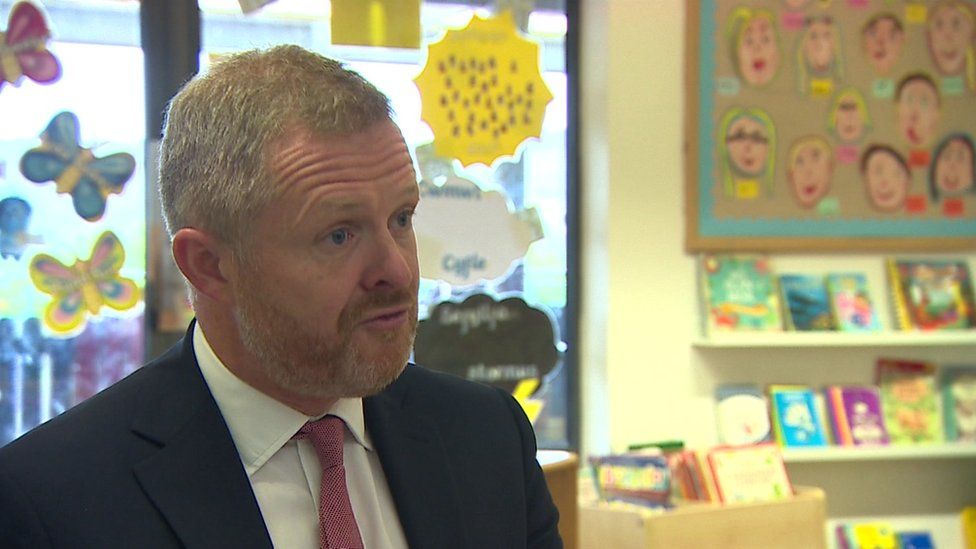 Jeremy Miles, who has short hair and a beard, wearing a suit and tie