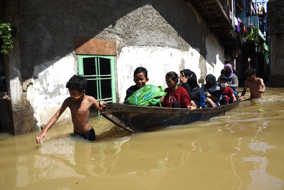 A family evacuate from their flooded home, following heavy rain in Bandung, Indonesia, on 3 November 2021