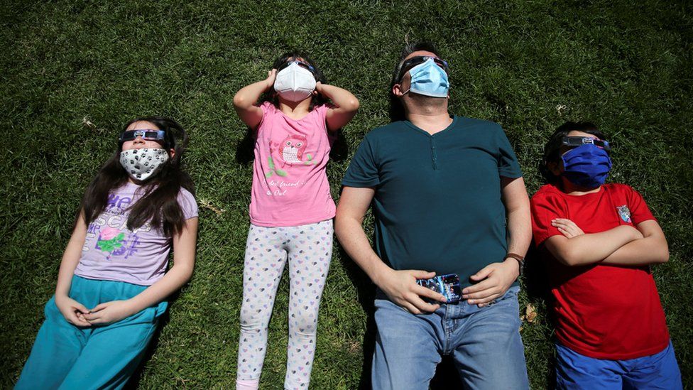 People use special protective glasses to observe the solar eclipse in Santiago, Chile, 14 December 2020