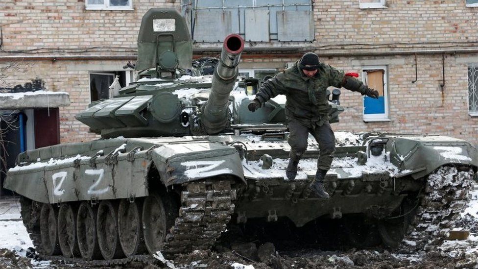 在顿涅茨克地区分离主义控制的沃尔诺瓦卡镇，在乌克兰-俄罗斯冲突期间被毁坏的住宅楼外，一名身穿没有徽章的亲俄军队服役人员从一辆涂有字母“Z”的坦克上跳下，乌克兰 2022 年 3 月 11 日。