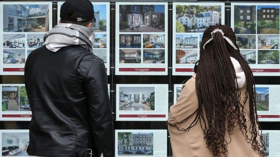 People looking at property adverts in an estate agent's window