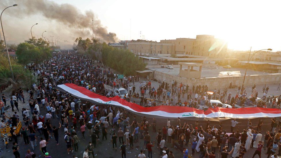 Iraqi protesters carry a giant Iraqi flag in Basra, 6 September 2018