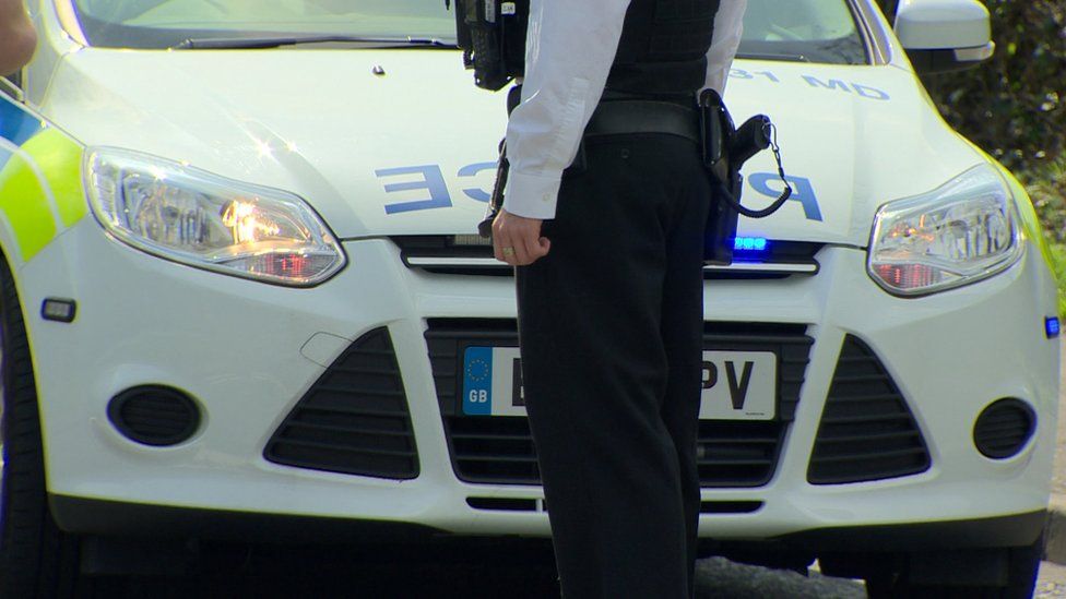 A police officer in front of a police car