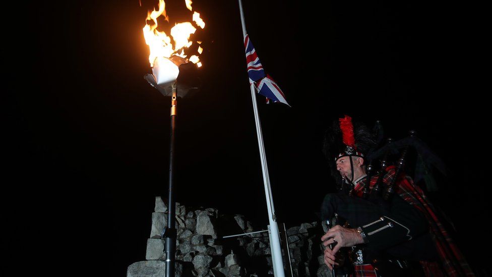 David Danks, of the City of Leeds pipe band, plays as a flame burns at Conisbrough Castle in South Yorkshire