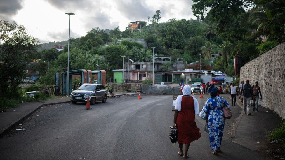 Two women walk towards a roadblock on the island of Mayotte