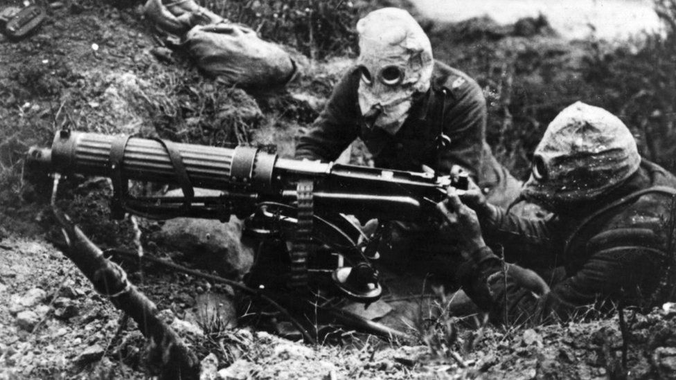 Soldiers wearing gas masks firing a gun
