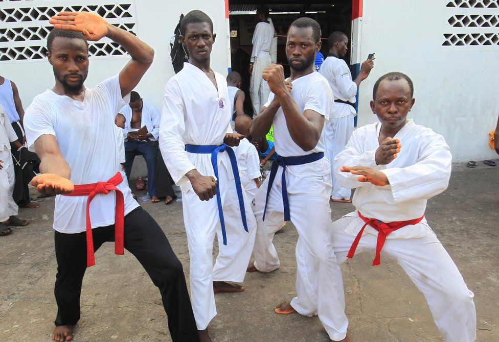 A group of young men strike taekwondo poses, two with red belts, two with blue in Monrovia, Liberia - Sunday 20 November 2016