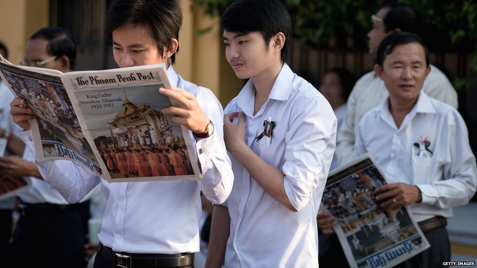 Men read newspapers as they wait outside the Royal Palace in the Cambodian capital Phnom Penh before being paying their final respects to former King Norodom Sihanouk on 2 February 2013.