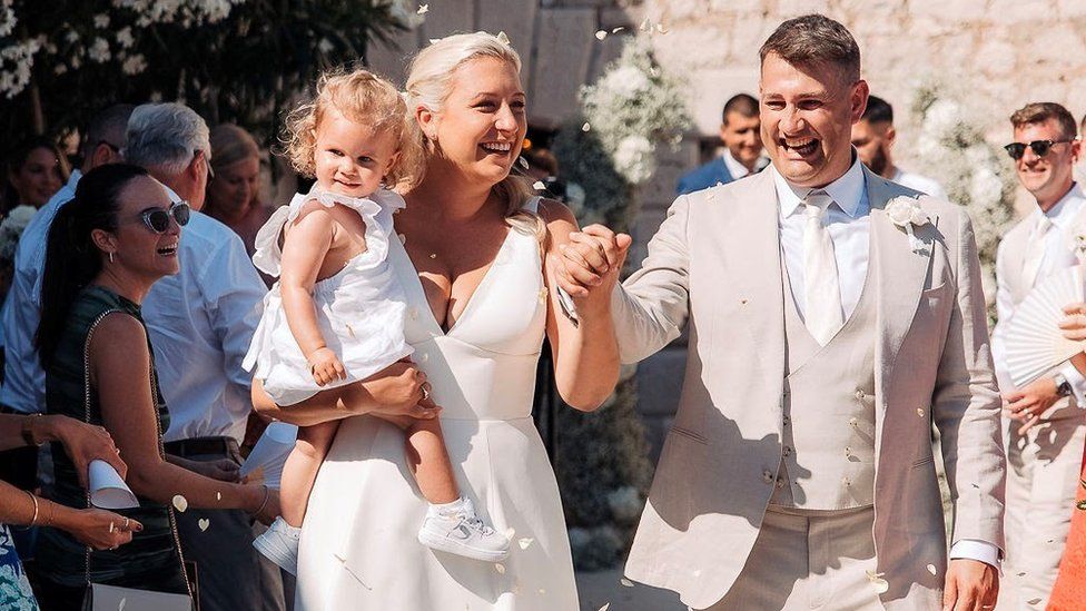 Sofia being carried by parents at their wedding