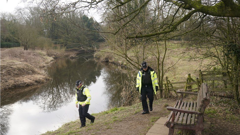 Police officers walking by the River Wyre near where Nicola Bulley's mobile phone was found