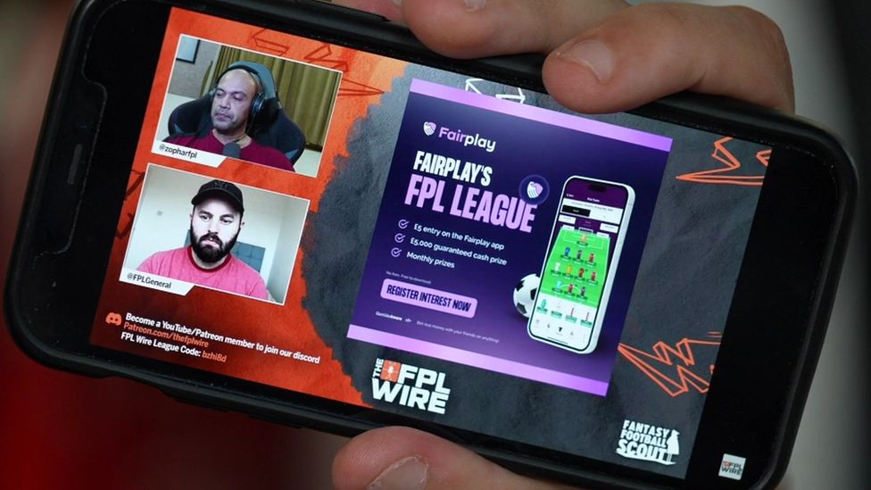 A phone showing an advert while people play FPL