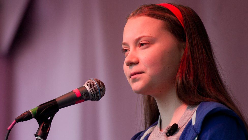 Greta Thunberg speaking in to a microphone at a rally.