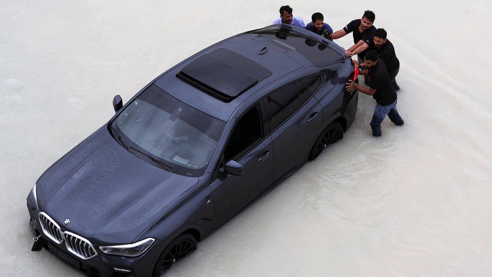 People push a car during a heavy rainfall in Dubai, United Arab Emirates, 16 April 2024.