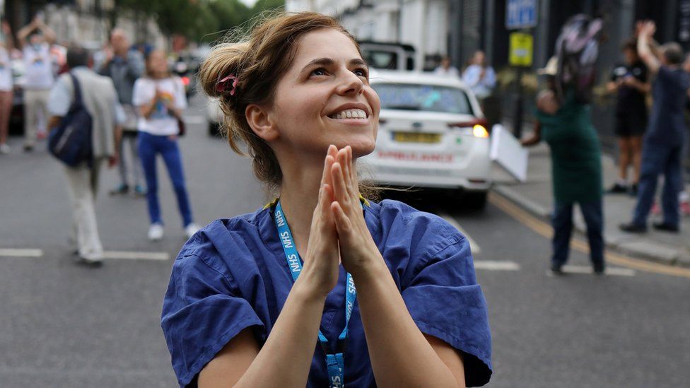 An NHS worker applauds in the street