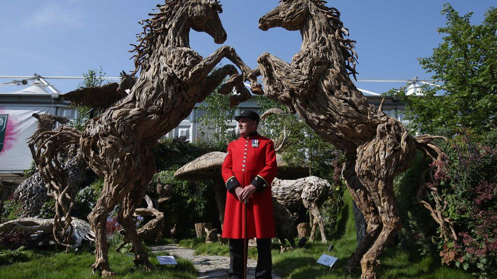 Chelsea pensioner in front of horse sculptures