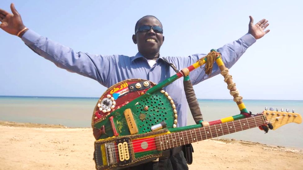 Noori with his "tambo-guitar" with him arms out near Port Sudan in Sudan