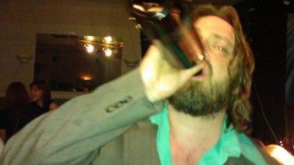 Old photo of now recovering alcoholic Gene Davies swigging from a bottle of booze at a club