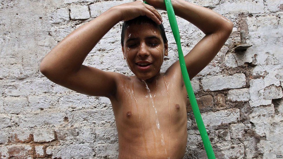A young Pakistani cools off in Peshawar, Pakistan, 25 June 2015.