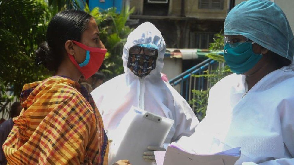 Municipal workers in hazmat suits talk to people waiting for a checkup at a municipal health camp during a government-imposed nationwide lockdown as a preventive measure against the COVID-19 coronavirus, in Kolkata on April 29, 2020.