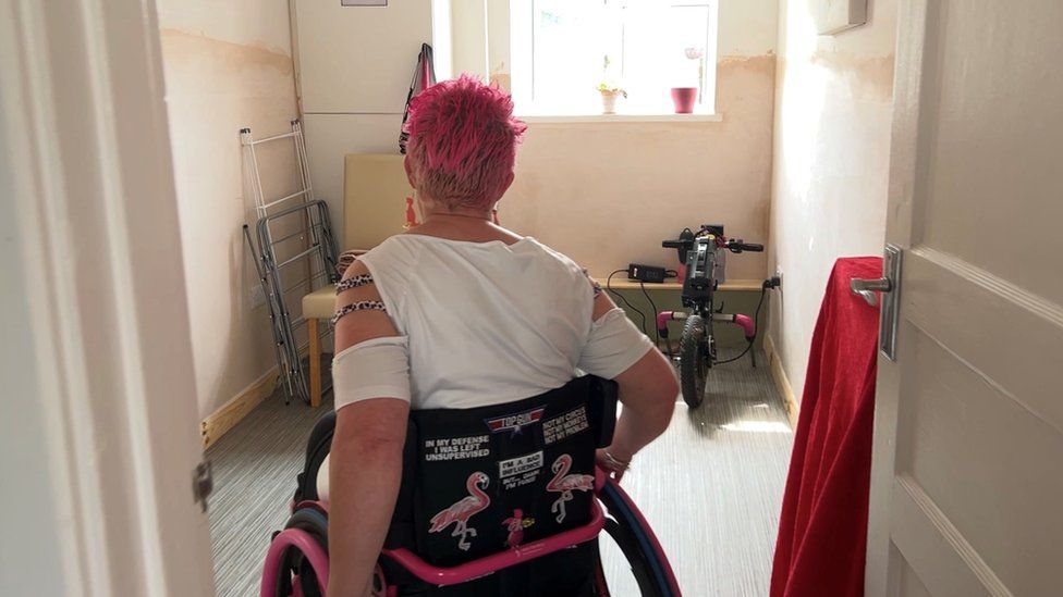 Mel Humphreys entering her empty dining room in her wheelchair.