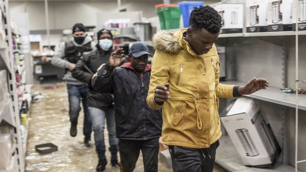 Suspected looters who surrendered to armed private security officers are marched outside, in a flooded mall in Vosloorus, on 13 July 2021