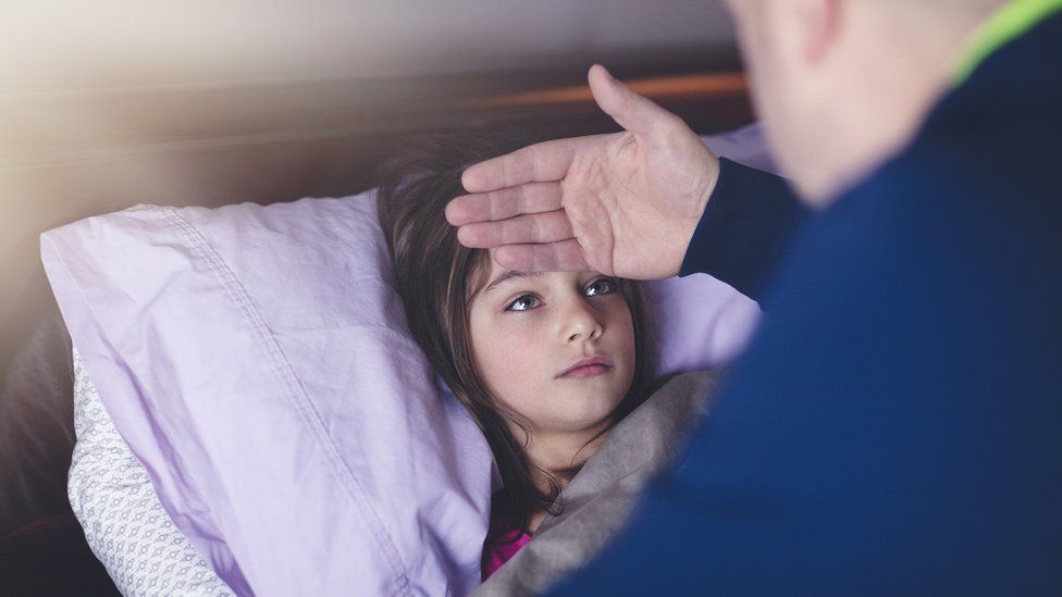 father feeling girl's forehead for temperature