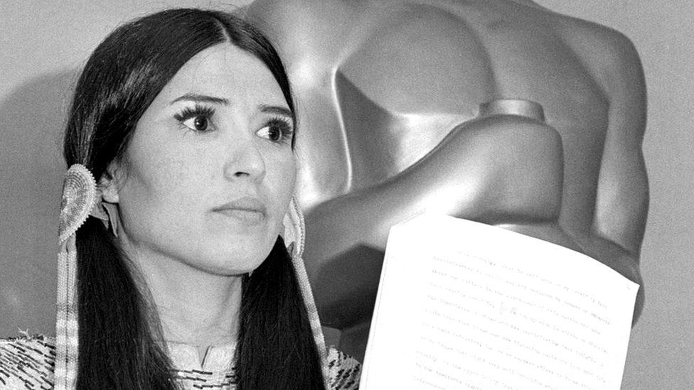 Littlefeather holds Brando's speech in front of an Oscar statue