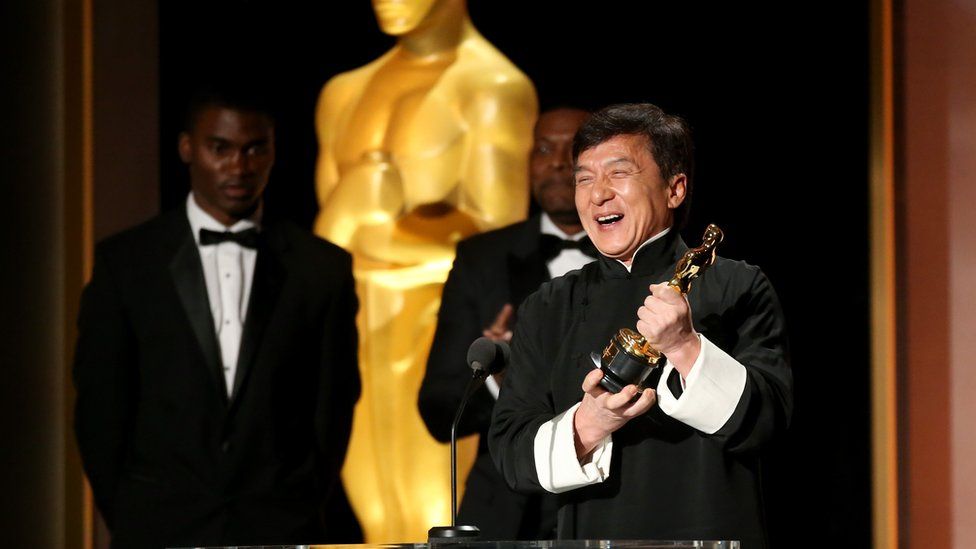 Jackie Chan holds up his honorary Oscar